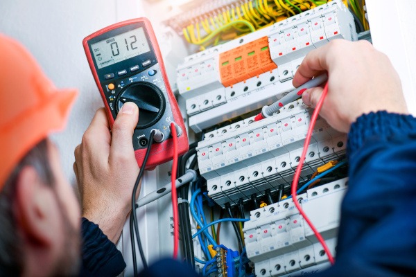 Electrician installing electric cable wires and fuse switch box. Elektriker misst Strom bei Elektroinstallation in Bonn